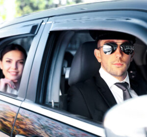 Limo Driver smiling at the camera with a happy customer at the back for limo services in New York