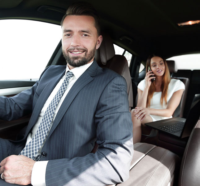 Limo Driver smiling at the camera with a happy customer at the back for place to place limo services in New York