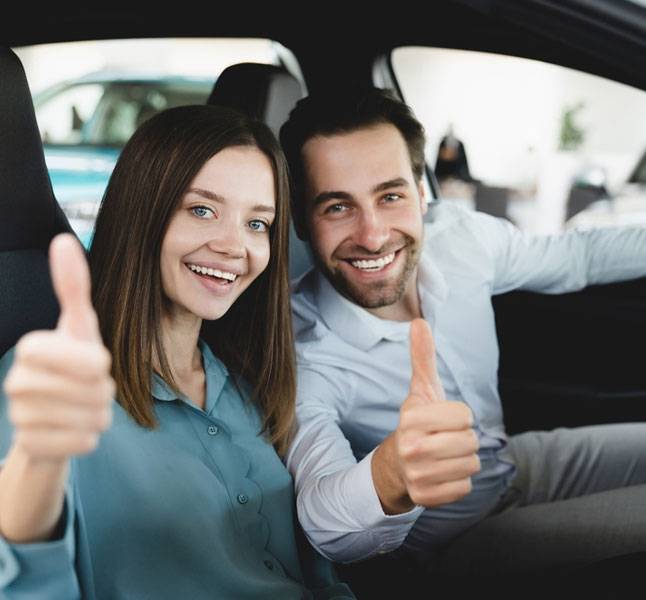 A couple happily showing thumbs up in a car on their anniversary