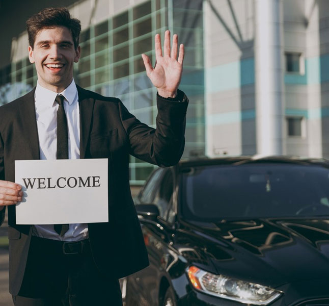 Limo greeter welcoming the passenger with a welcome card for airport transfer