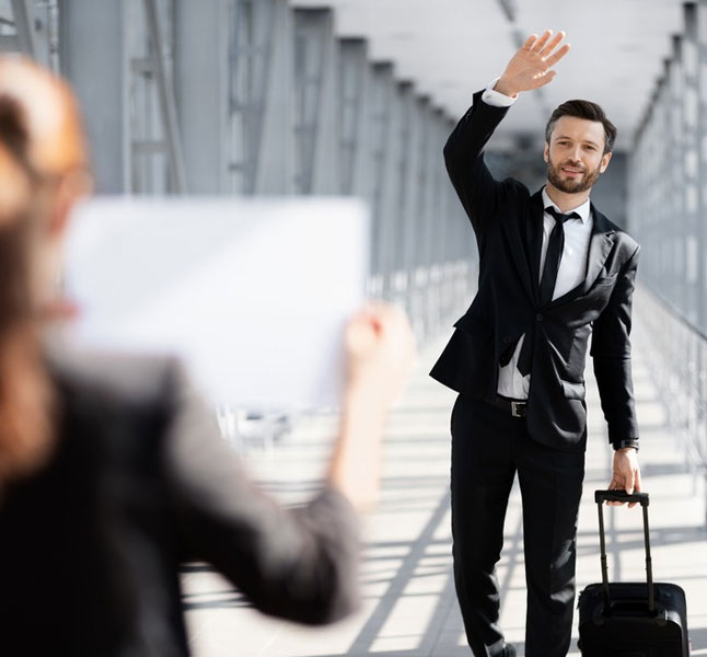 A passenger waving at a limo service greeter at the airport for limo services near me